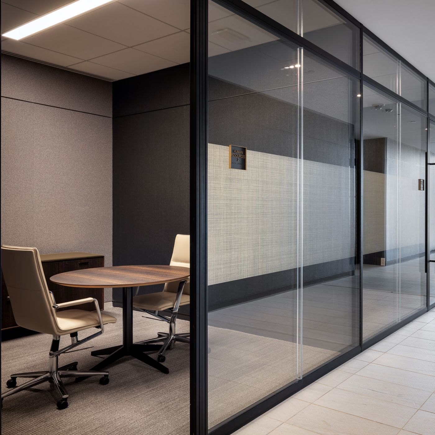 A round SESSIONS conference table is paired with a HALO credenza in Fumed Figured Eucalyptus.